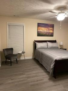 a bedroom with a bed and a chair and a ceiling fan at A Touch of Sunshine Ideal For Long Term Stays in Fayetteville