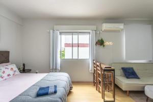 1 dormitorio con cama, sofá y ventana en Aconchegante e ensolarado!, en Porto Alegre
