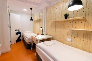a room with two beds and a table with a lamp at Koala Hostel Mercado in Alicante