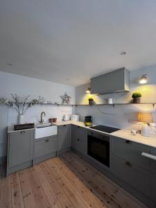 a kitchen with white cabinets and a wooden floor at Efail Fach in New Quay