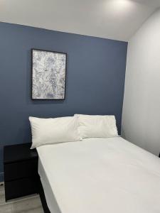 a bedroom with a white bed with a blue wall at Everlight Basildon House in Basildon