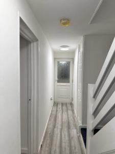 an empty hallway with a white door and a staircase at Everlight Basildon House in Basildon