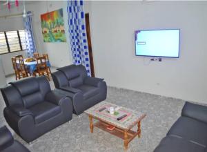 ein Wohnzimmer mit Sofas, einem Tisch und einem TV in der Unterkunft Maison d'hôte avec paillote in Palimé