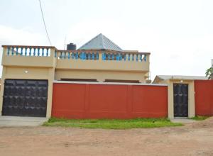 una casa con una valla roja delante de ella en Maison d'hôte avec paillote, en Palimé