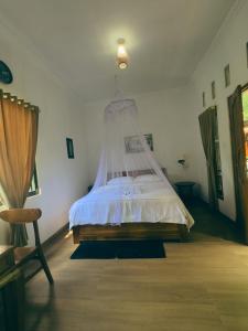 a bedroom with a bed with a mosquito net at Homestay Sente in Munduk