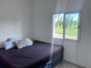 Bett in einem Zimmer mit Fenster in der Unterkunft quincho el atardecer in Santa Lucía
