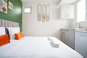 een wit bed in een keuken met oranje kussens bij Green studio cosy and confortable - IV in Parijs