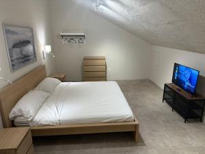 - une chambre avec un lit blanc et une télévision dans l'établissement Departamentos Flamboyant, à Acapulco