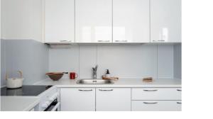a white kitchen with a sink and white cabinets at City Apartment in Tampere
