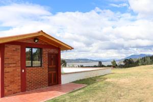 a small brick building on a hill with a lake at Alojamiento Villa Doralis in Guatavita +7 photos
