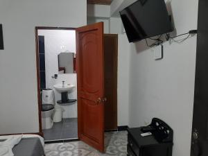 Hotel Neiva Providencia في نيفا: حمام مع مرحاض وتلفزيون على جدار