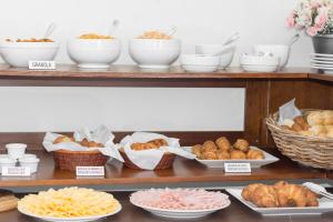a shelf with plates of pastries and baskets of bread at Palm Beach Plaza Hotel in Montevideo