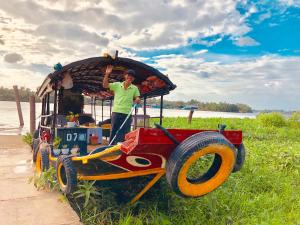 un homme debout à l'arrière d'un tracteur dans l'établissement Mango Home Riverside, à Ben Tre