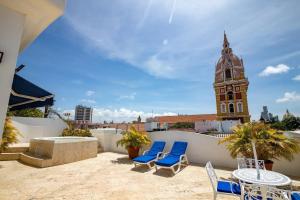 a rooftop patio with chairs and a clock tower at Edificio ubicado en el centro de la ciudad dentro de la ciudad amurallada Edificio Ayos in Cartagena de Indias