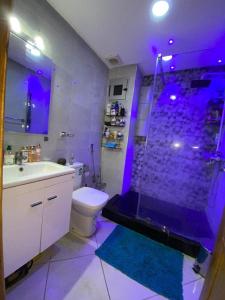 La salle de bains est pourvue d'une douche et de toilettes avec des lumières violettes. dans l'établissement Ibtissam home, à Kenitra