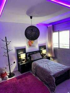 - une chambre avec un éclairage violet et un lit avec un ours en peluche dans l'établissement Ibtissam home, à Kenitra
