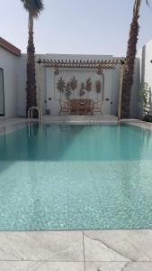 a swimming pool with a table and palm trees at شاليه أوڤال Oval Chalet in Al Jubail