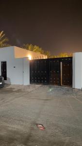 una cerca frente a una casa blanca por la noche en شاليه أوڤال Oval Chalet, en Al Jubail
