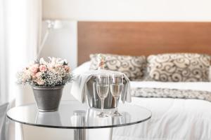 a table with two glasses and a vase with flowers at Palm Beach Plaza Hotel in Montevideo