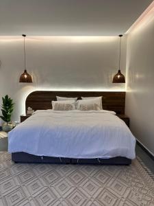 شاليه أوڤال Oval Chalet في Al Jubail: غرفة نوم بسرير ابيض كبير بها قلادتين انارة