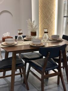 a dining room table with plates and bowls and chairs at شاليه أوڤال Oval Chalet in Al Jubail