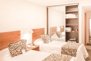 a hotel room with two beds and a mirror at Palm Beach Plaza Hotel in Montevideo