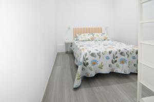 a white bedroom with a bed with a floral bedspread at The Safe Point Suites Tablero in El Tablero