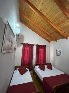 two beds in a room with red curtains at ROOMS EMILIANO Castle of Kruja in Krujë