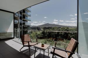 two chairs and a table on a balcony with a view at Center 1-Bed with Gym, BBQ and Stunning Views in Canberra