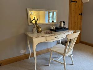 a desk with a mirror and a chair in a room at The Coach House in Chedworth