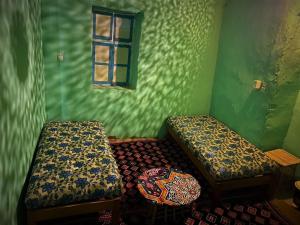 a green room with two beds and a window at Humble Nubia in Aswan
