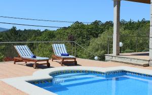 a pair of chairs sitting next to a swimming pool at Exclusiva casa con piscina en Gondomar in Gondomar