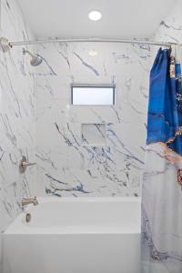 uma casa de banho com um chuveiro e uma parede em mármore. em Bluebonnet Waterfront Cottage with Hot Tub em Fredericksburg