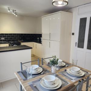 a kitchen with a wooden table with plates on it at Exquisite Stays Free parking, fast WiFi, close to city centre in Kenton