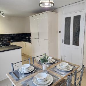 a kitchen with a wooden table with plates on it at Exquisite Stays Free parking, fast WiFi, close to city centre in Kenton +35 photos