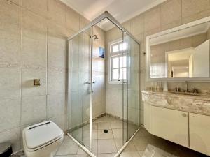 uma casa de banho com um WC e uma cabina de duche em vidro. em Luna Hotel Boutique - Beira Mar no Guarujá