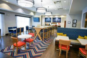 a waiting room with tables and chairs and a couch at Hampton Inn Greenville in Greenville