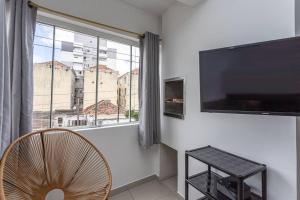 uma sala de estar com uma grande janela e uma televisão em Ensolarado e iluminado! em Porto Alegre