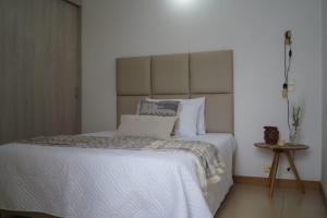 - une chambre dotée d'un grand lit avec des draps et des oreillers blancs dans l'établissement Apartamento el mirador, à Bello