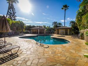 a swimming pool with chairs and a stone patio at Maui Beachside Retreat in Wailea
