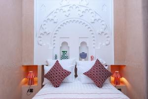 a bedroom with a bed with a white headboard and pillows at Riad Amalia in Marrakech