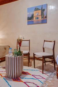 a living room with two chairs and a table with a vase at Riad Amalia in Marrakech