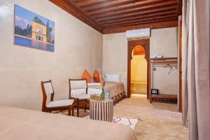 a bedroom with two beds and a table and chairs at Riad Amalia in Marrakech