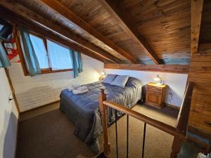 an attic bedroom with a bed and a wooden ceiling at Punto Sur Cabañas in El Bolsón