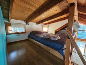 Cama en habitación pequeña con techo de madera en Punto Sur Cabañas en El Bolsón