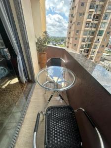 y balcón con mesa de cristal y sillas. en Apartamento Completo Próx Hangar en Belém