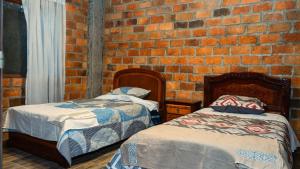 2 Betten in einem Zimmer mit Ziegelwand in der Unterkunft Casa Ensueño in Catamayo