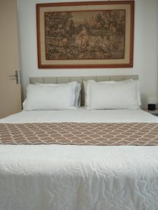 1 cama con 2 almohadas y una foto en la pared en Aconchegante apto, quadra do mar, no Tabuleiro! en Barra Velha