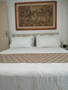 a bed with two pillows and a picture on the wall at Aconchegante apto, quadra do mar, no Tabuleiro! in Barra Velha