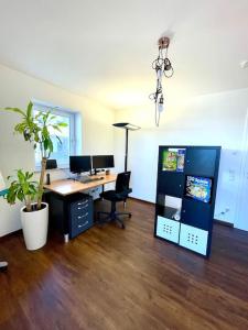 an office with a desk with two monitors and a plant at Highlight! Stilvolle 100m2 mit Büro Nähe München in Mühldorf